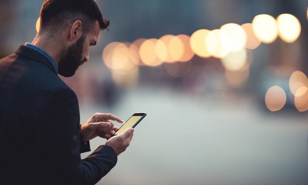 A person using a smartphone with blurred bokeh lights